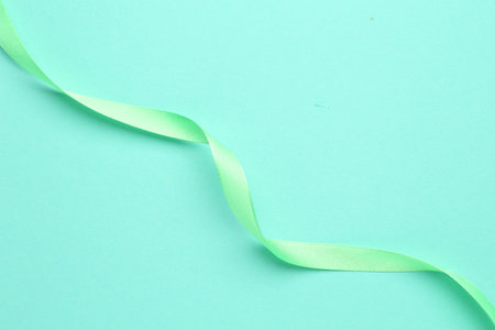 Beautiful light green ribbon on turquoise background, top viewの写真素材