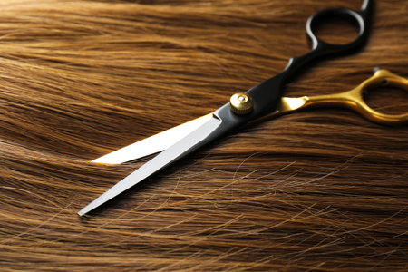 Scissors on beautiful shiny hair, closeup viewの写真素材