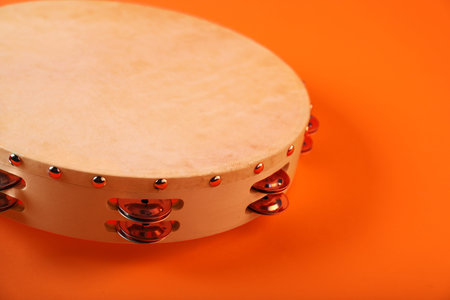 Tambourine on orange background, closeup. Traditional musical instrumentの写真素材