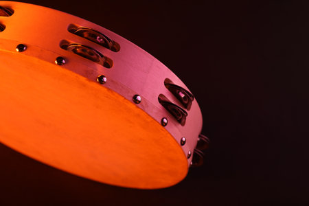 Tambourine in color light on black background, closeup. Space for textの写真素材
