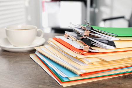 Many folders with documents and drink on wooden desk, closeupの写真素材