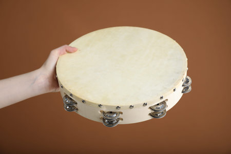 Woman playing tambourine on brown background, closeupの写真素材
