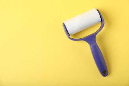 One lint roller on yellow background, top view. Space for textの写真素材