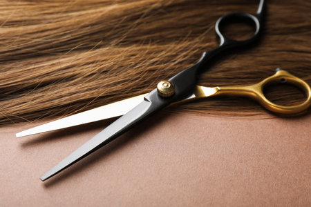 Beautiful hair and scissors on light brown background, closeupの写真素材