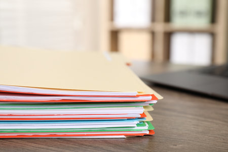 Many folders with documents and laptop on wooden desk, closeup. Space for textの写真素材