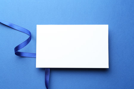Beautiful ribbon and blank card on blue background, flat layの写真素材
