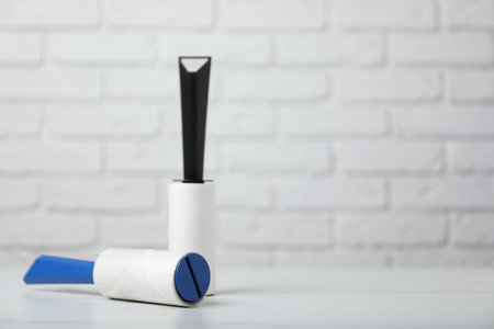 Lint rollers on white marble table against brick wall, closeup. Space for textの写真素材