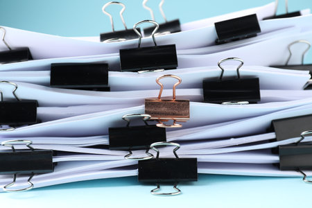 Many documents with binder clips on light blue background, closeupの写真素材