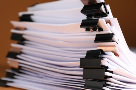 Many documents with binder clips on brown background, closeupの写真素材