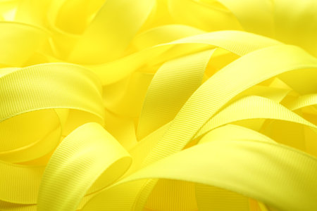 Beautiful yellow ribbons on color background, closeupの写真素材