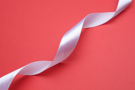 Beautiful white ribbon on red background, closeupの写真素材