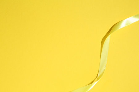 Beautiful ribbon on yellow background, top view. Space for textの写真素材