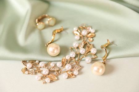 Beautiful gold jewelry and silk cloth on beige background, closeupの写真素材