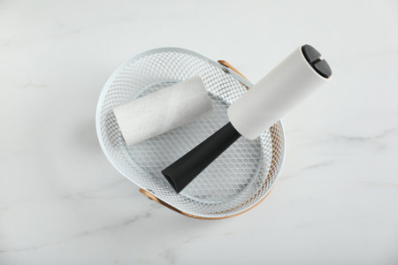 Lint roller and adhesive roll in basket on white marble table, top viewの写真素材