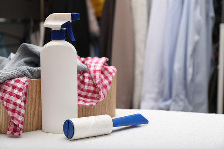 Lint roller, bottle of cleaning product and clothes on towel indoors, space for textの写真素材