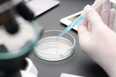 Research in genetics. Scientist with micropipette and Petri dish working at table in laboratory, closeupの写真素材