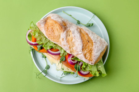 Delicious sandwich with prosciutto, cheese and vegetables on green background, top viewの写真素材