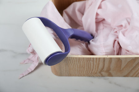 Lint roller and cloth in wooden box on white marble table, above viewの写真素材
