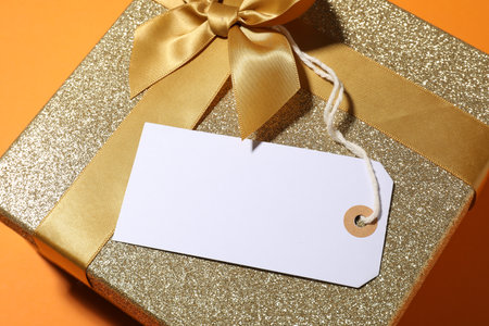 Blank tag and gift box on orange background, above viewの写真素材