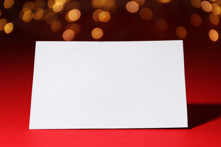 Blank card on red background with blurred lights, closeup. Bokeh effectの写真素材