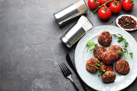 Salt and pepper shakers, meatballs on gray table, flat lay. Space for text