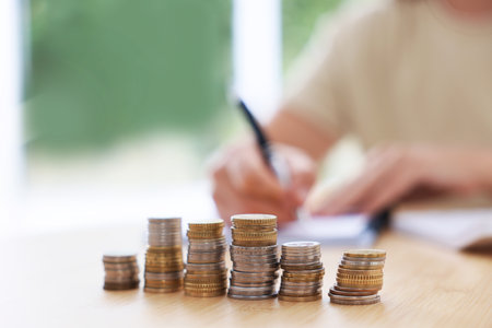 Woman working at wooden table indoors, focus on stacks of coinsの写真素材
