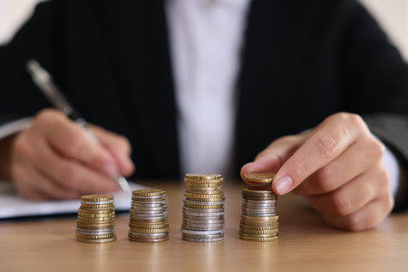 Woman counting coins at wooden table indoors, selective focusの写真素材