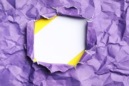 Blank card on yellow background, view through hole in torn purple paperの写真素材