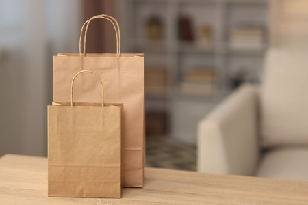 Paper shopping bags on wooden table indoors. Space for textの写真素材