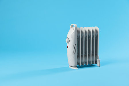 Electric heater on light blue background. Space for textの写真素材