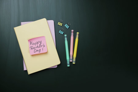 Note with the phrase Happy teacher's day and stationery on green background, flat lay. Space for textの写真素材