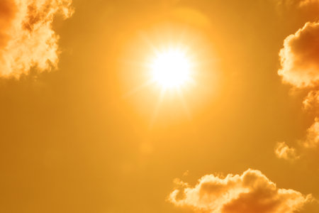 Bright sun and clouds in orange sky during hot summer weatherの写真素材