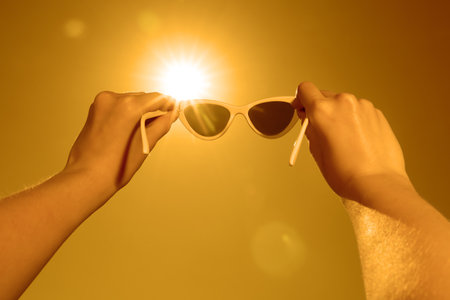 Woman holding sunglasses against bright sun, closeupの写真素材
