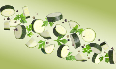 Fresh zucchini pieces and parsley falling against light green backgroundの写真素材