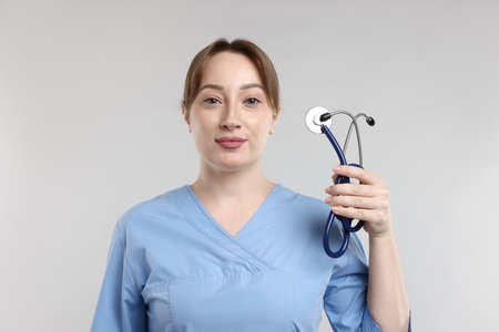 Portrait of professional nurse with stethoscope on light gray backgroundの写真素材