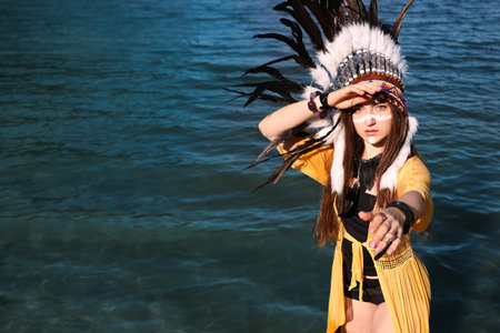 Shaman woman in native American Indian headdress with face painting in river water.の写真素材