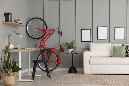 Red bicycle and stylish furniture near gray wall indoorsの写真素材