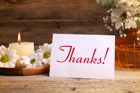 Thank you card, candle and flowers on wooden tableの写真素材