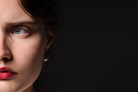 Sad woman crying on black background, closeup
