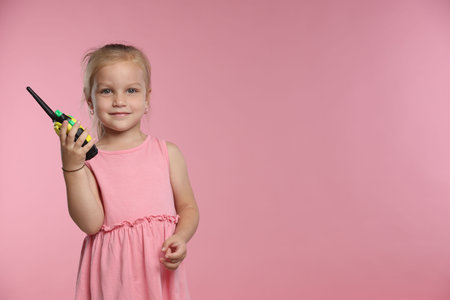 Little girl with walkie talkie toy on pink background, space for textの写真素材
