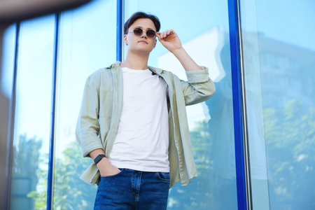Man in stylish jeans near building outdoors, low angle viewの写真素材