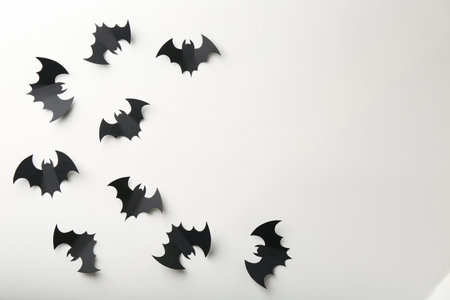 Halloween decor. Black paper bats on white background, flat lay. Space for text