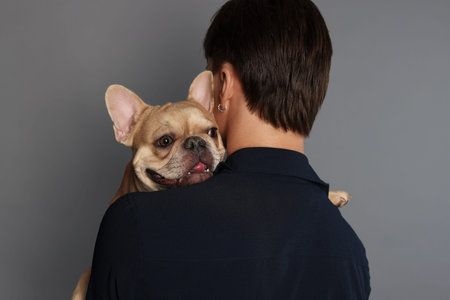 Man holding his cute bulldog on gray background, back viewの写真素材