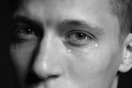 Sad man crying on dark background, closeup. Black and white effectの写真素材