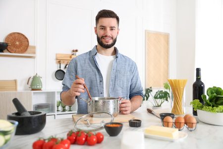 Smiling man cooking at table in kitchen