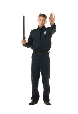 Young policeman in uniform with baton showing stop gesture on white background