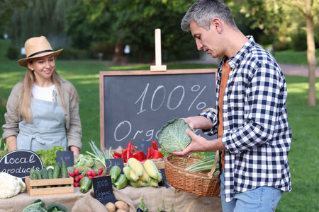 Man choosing fresh vegetables from stall at farmer's marketの写真素材