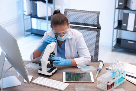 Research in genetics. Scientist working with microscope at table in laboratoryの写真素材