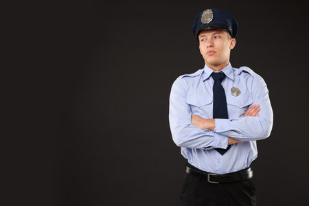 Young policeman in uniform on black background, space for textの写真素材