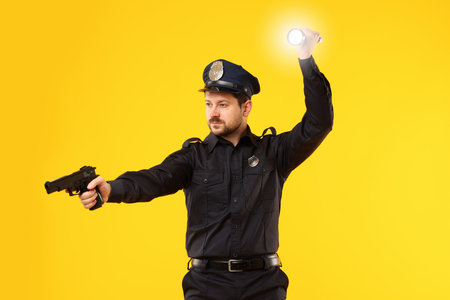Policeman in uniform with gun and flashlight on yellow background